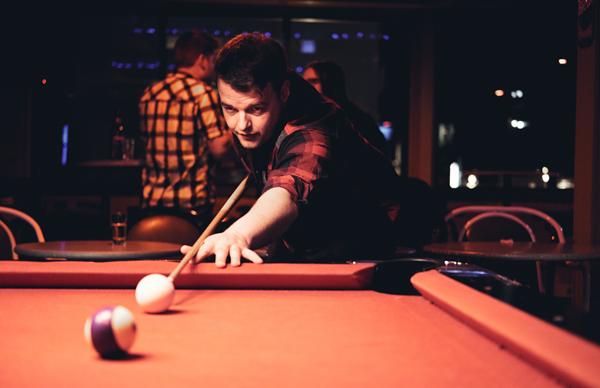 Guy playing Pool at a Bar