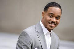 Man in grey suit seated smile